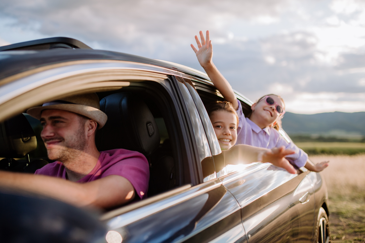 Happy family enjoying drive in their electric car.